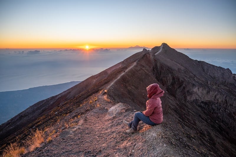 hiker watching the sunrise at the Mount Agung summit